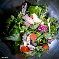 Baby green salad with carrot, apple, dried salami, and table cheese with a lemon vinaigrette